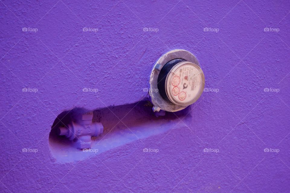 An exterior wall of a purple home with an external utility meter in San Miguel de Allende.