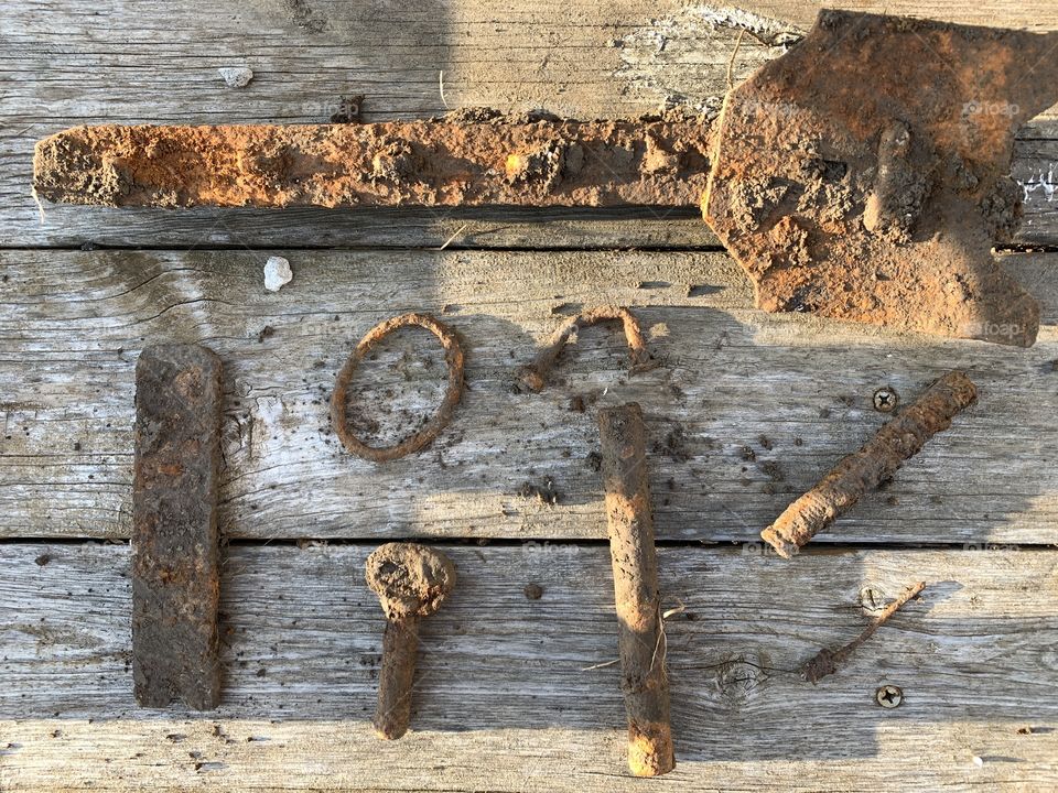 Found, rusted, vintage, iron implements for farm use on wooden surface, circa early 1900s