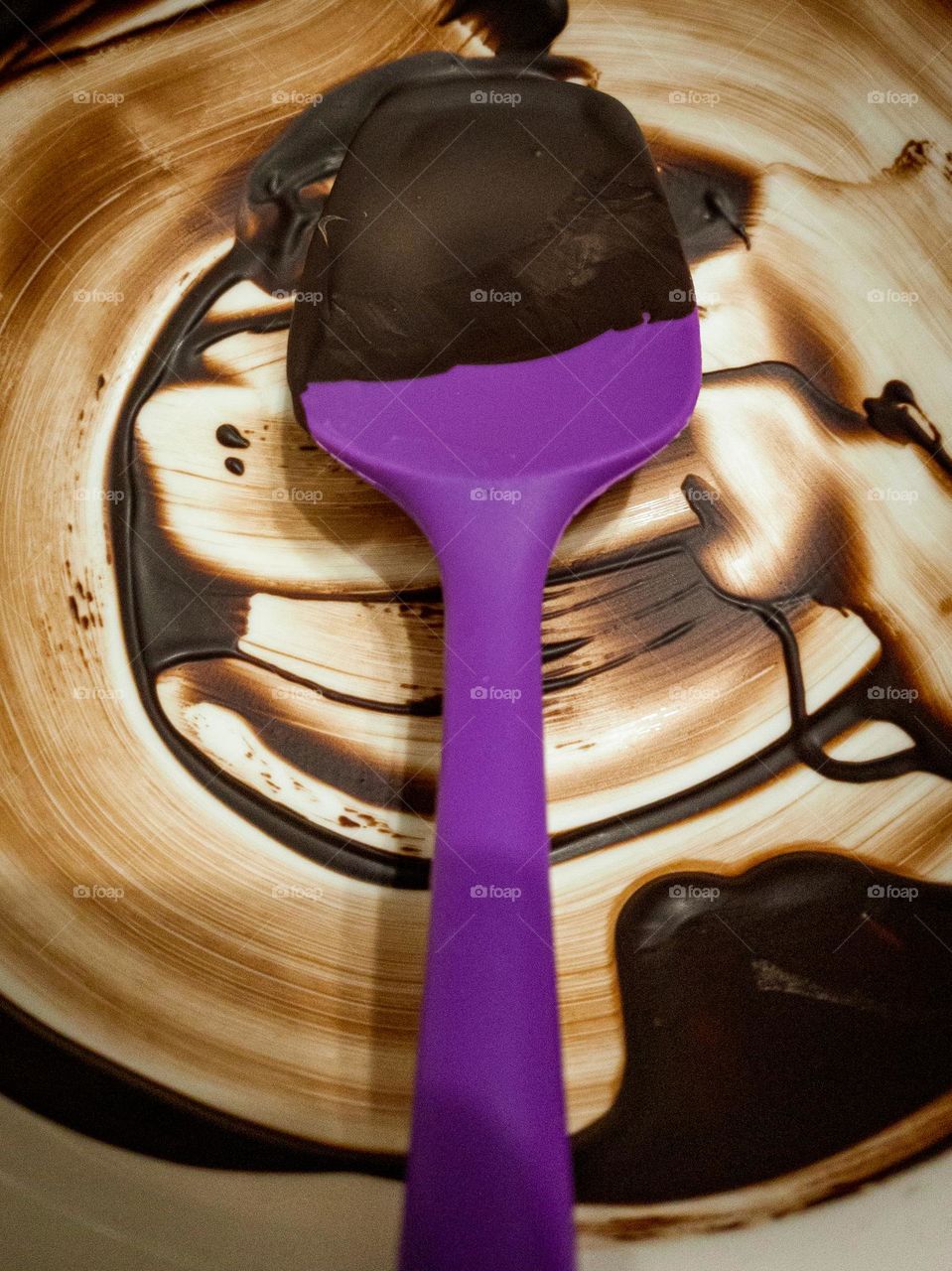 purple silicone spoon in a white bowl with chocolate's leftover