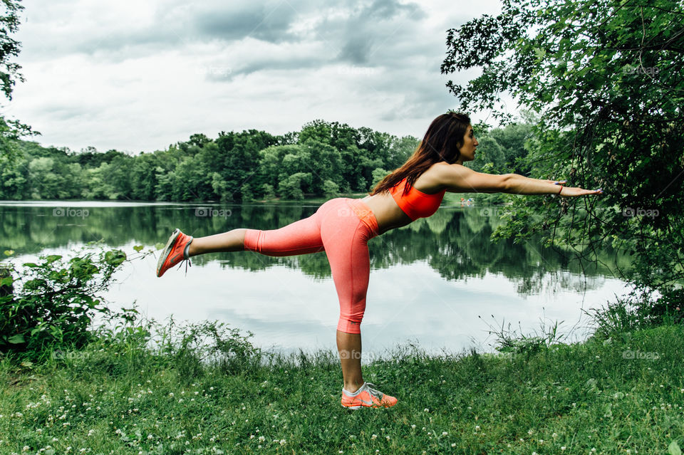 Young woman doing yoga at lake side