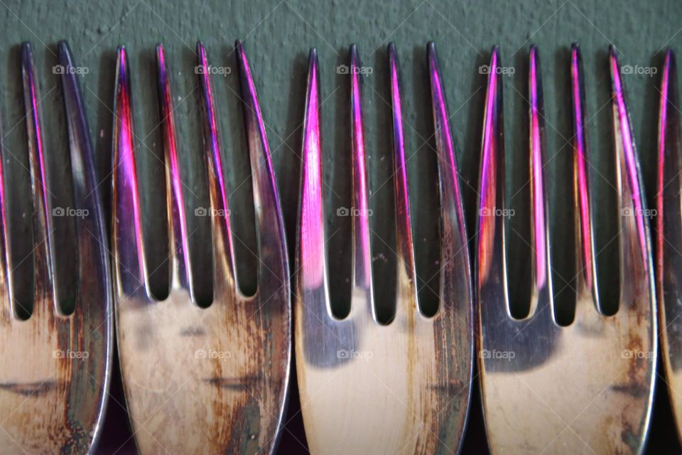 Close up of illuminated silver forks on green background 