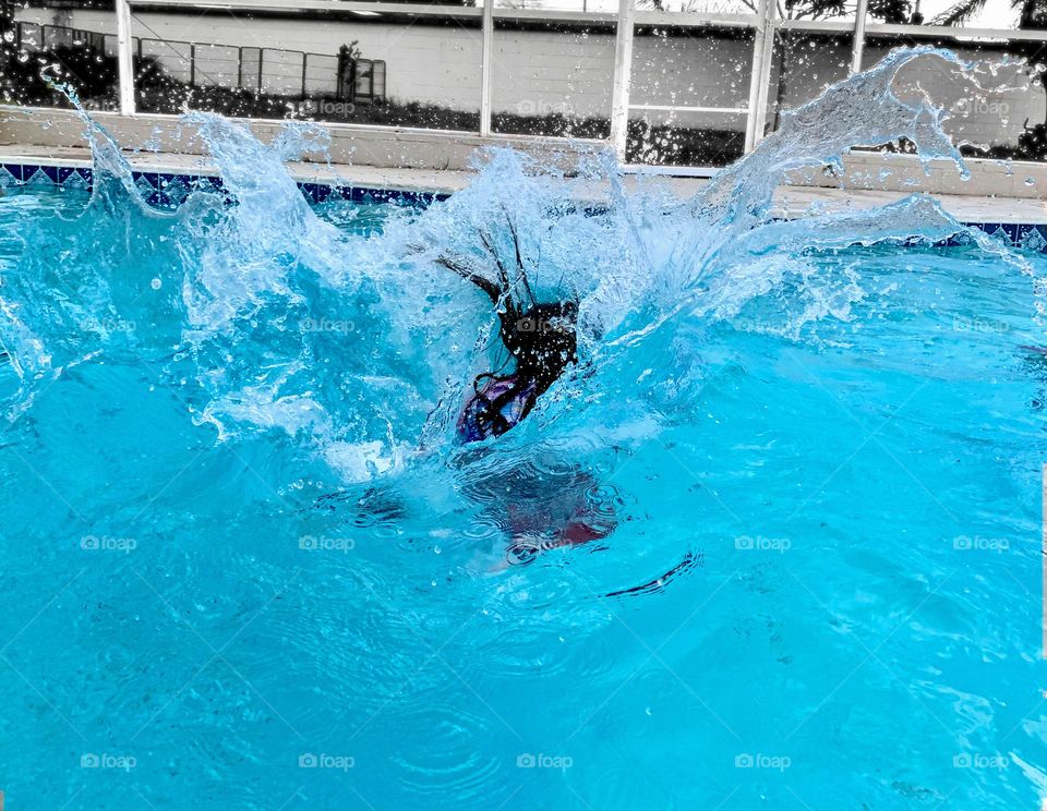 Girl Jumping In The Pool Caught In Action With Water Splash All Around Her With Black And White Background.