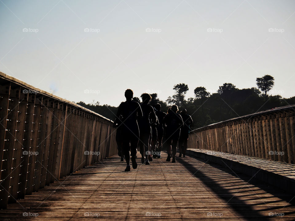 Running group on a wooden bridge at sunrise 