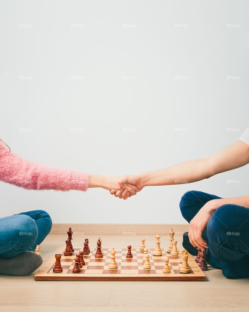 Chess game is over. Girl and boy handshaking after finished chess game, thanking for playing. Copy space for text at the top of image