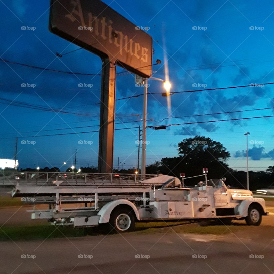 Old fire ladder truck at an antique shop at sunset