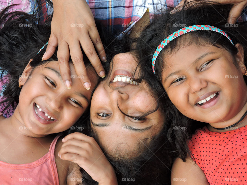 Directly above view of woman with her daughters lying and smiling