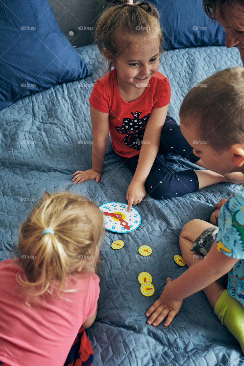 Kids learning how to tell time from clock and set the hands in the correct position. Teaching preschoolers tell time. Candid people, real moments, authentic situations