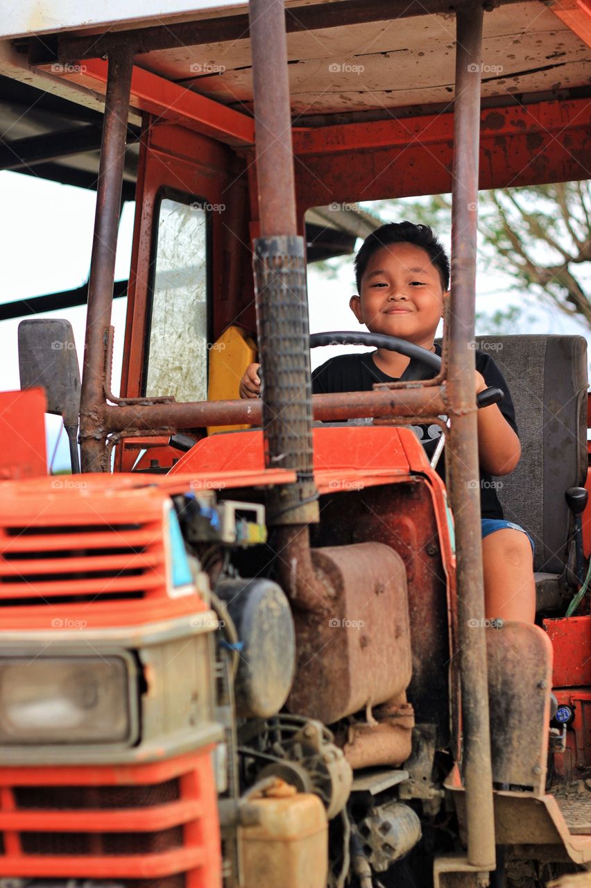 A boy from a farm. Playing with his fathers tractor with full of imagination driving it one day. 