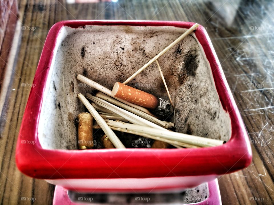 Cigarette butt with ash in ashtray