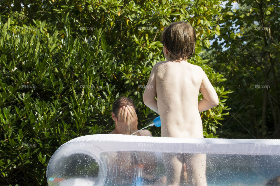 Rear view of a nude child splashing water with water gun