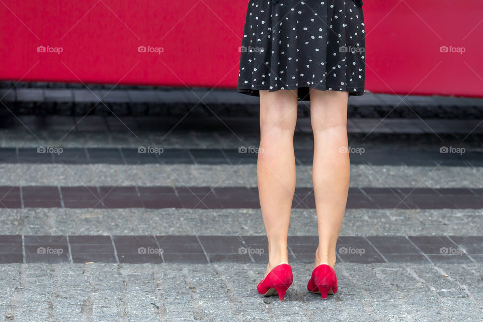 Woman in a red shoes waiting for a bus in the street