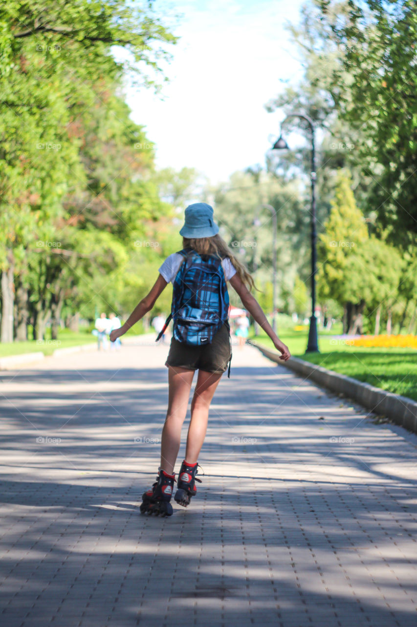 Rear view of a girl rides on roller skates