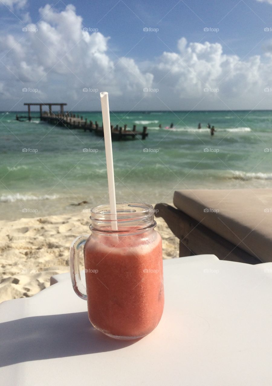 A strawberry smoothie with a beach view