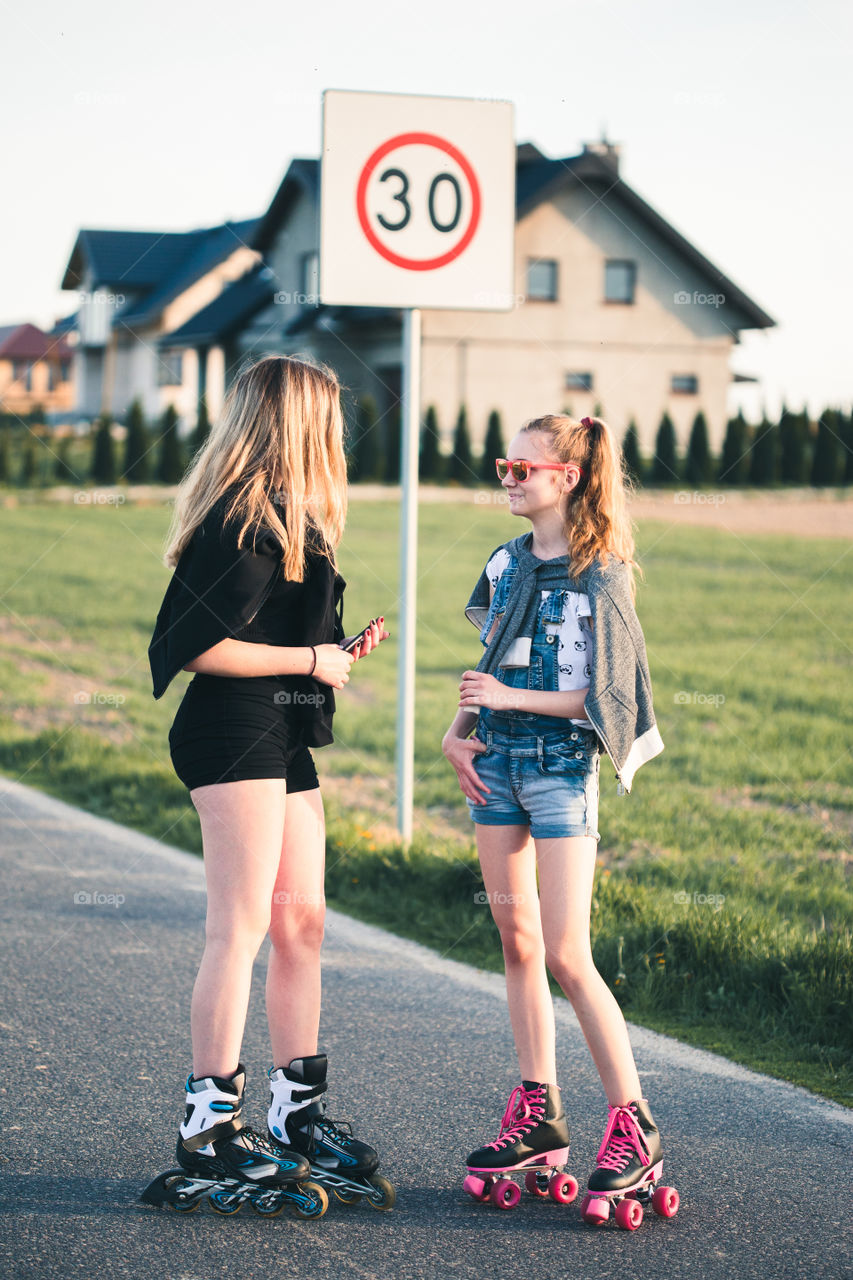 Teenage smiling happy girls having fun rollerskating, spending time together on summer day. Teenage smiling happy girls having fun walking outdoors, hanging, spending time together on summer day. Real people, authentic situations