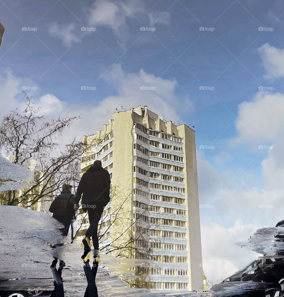 two people are reflected in a puddle