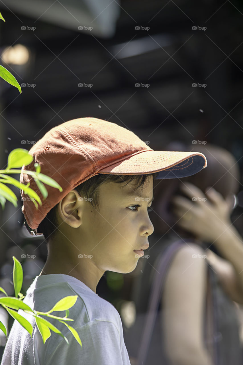 Portrait of Asian boy wearing a red cap and white  shirt is smile and Play water mist.