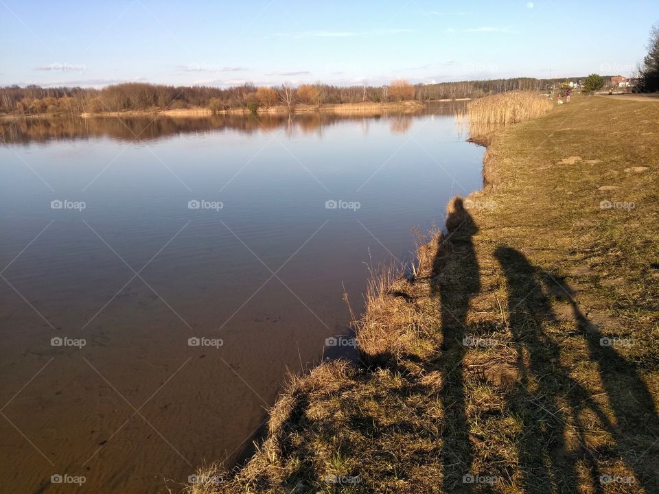 light and shadows person with bike on a grass lake shore spring time, beautiful sunset landscape