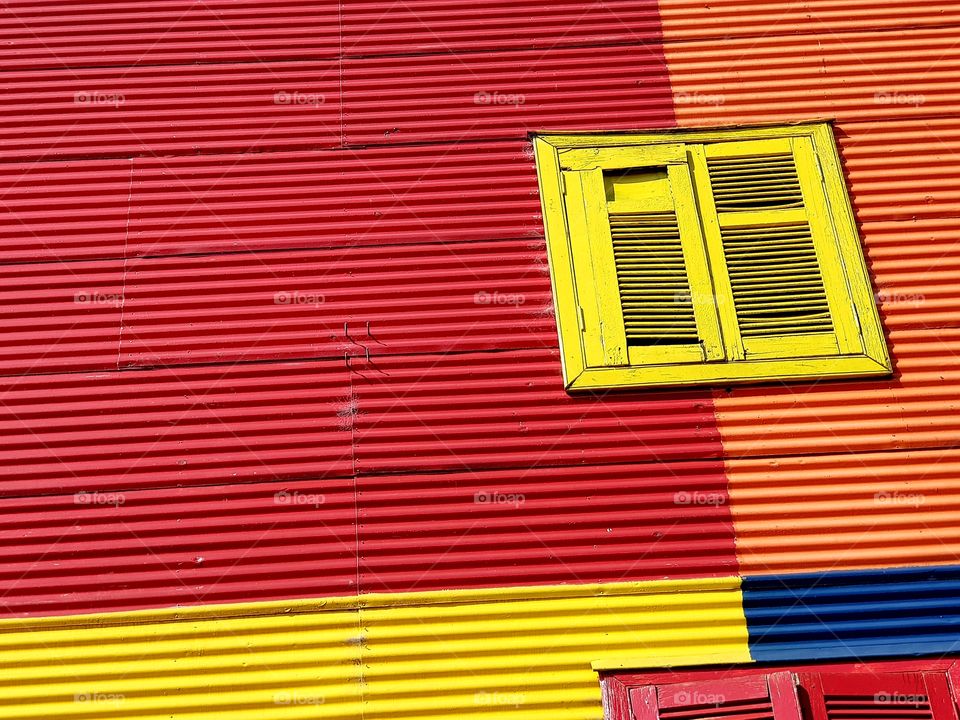 yellow window on a red and orange colorful facade in La Boca Argentina