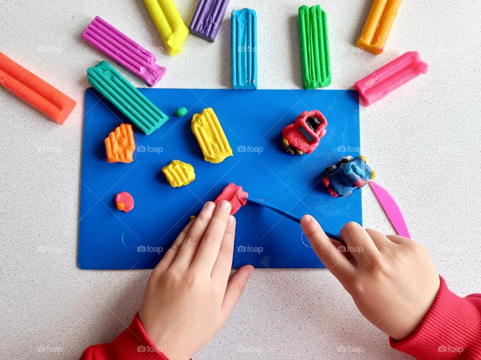 a child sculpts a car from plasticine.