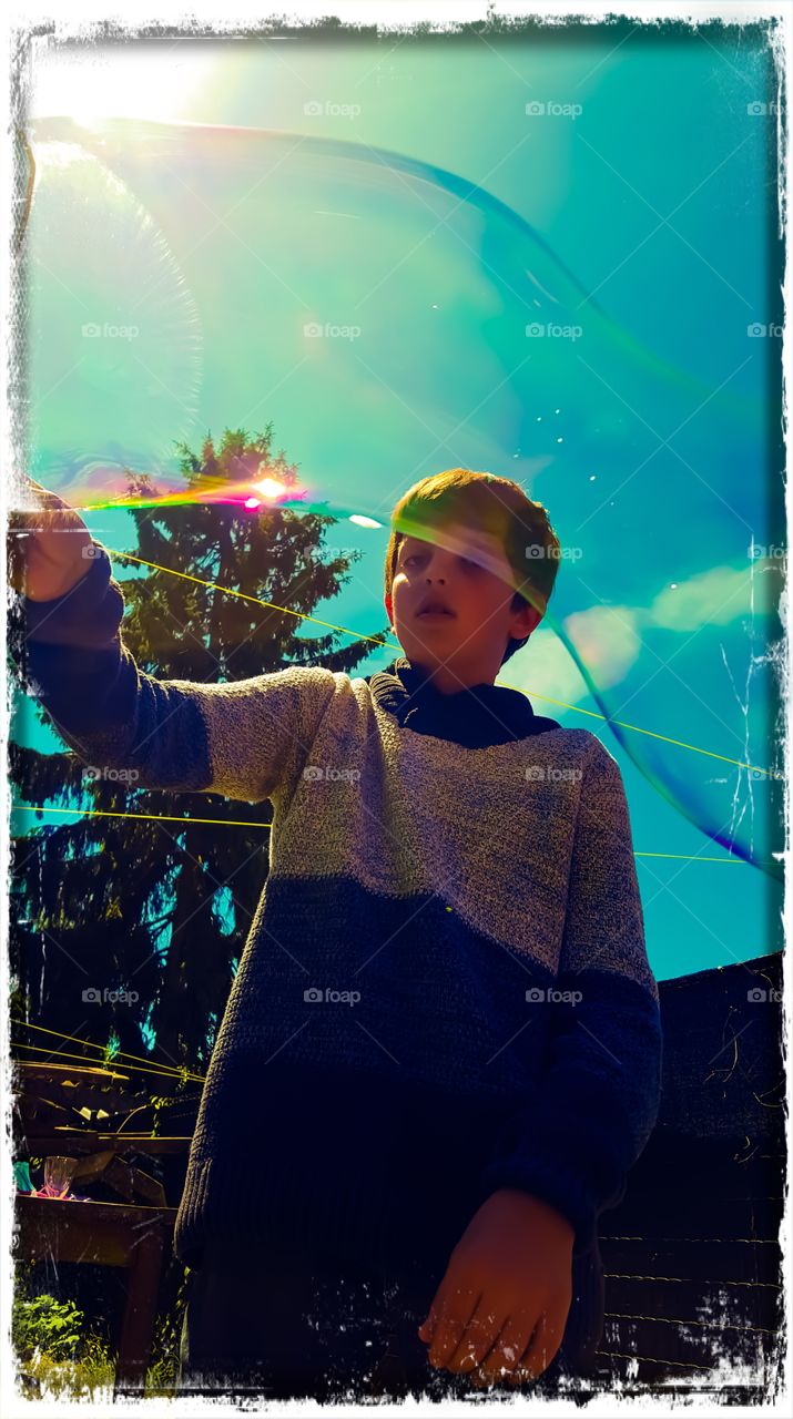 My boy playing in the garden blowing soap bubbles in summertime