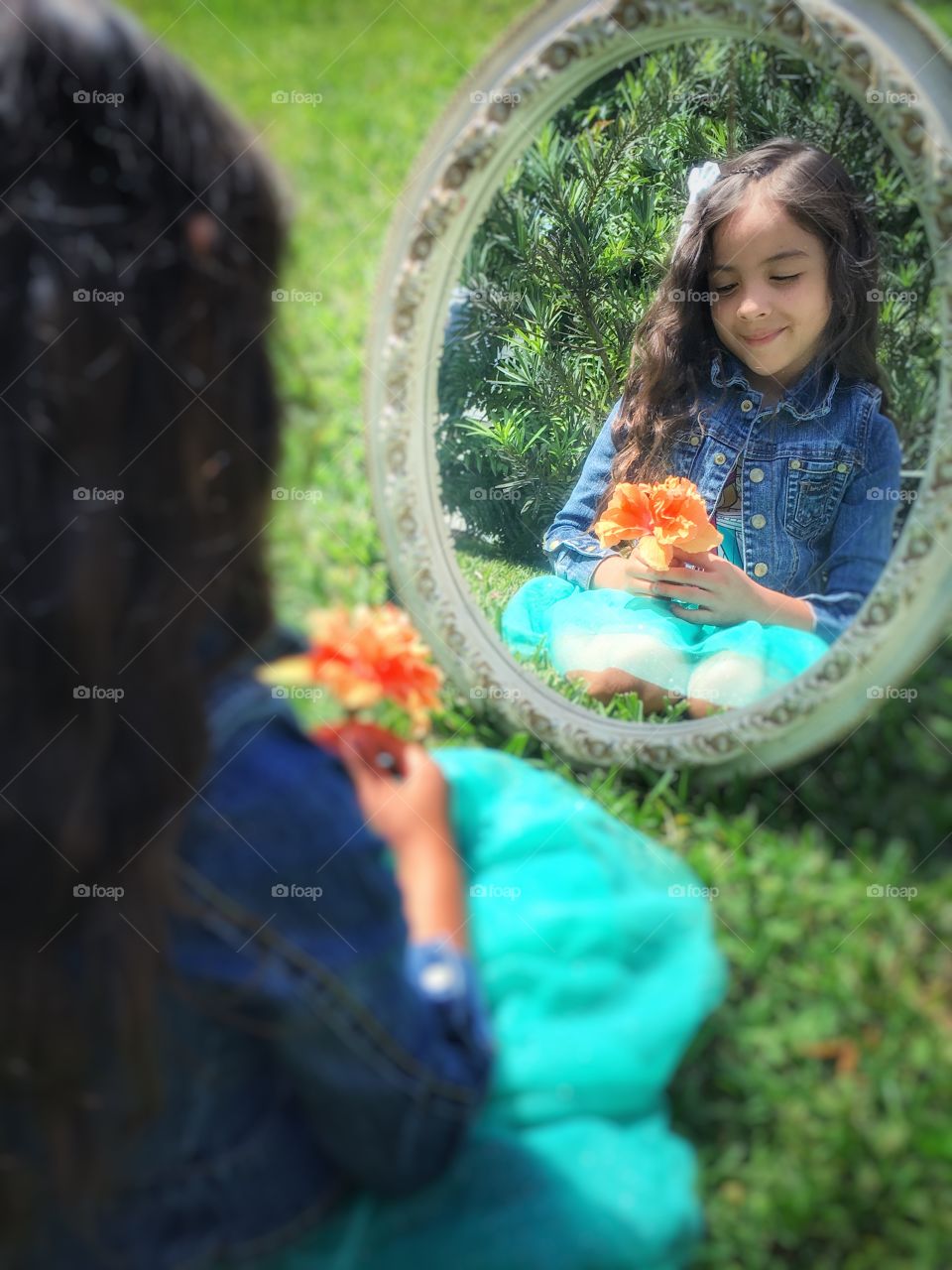 Girl with flower in hand reflecting on mirror