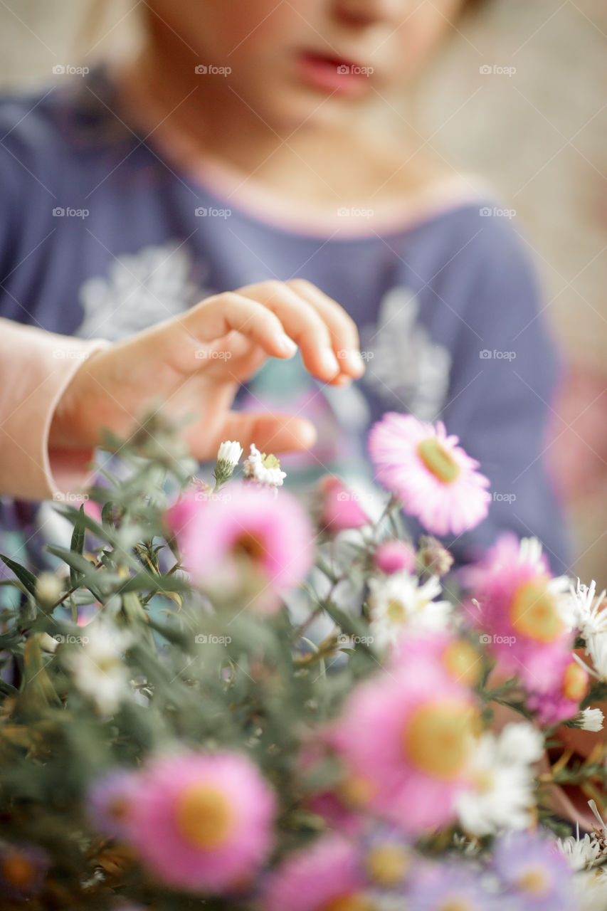 Little sisters in pajamas with bouquet of autumn flowers at home. Hand close up 