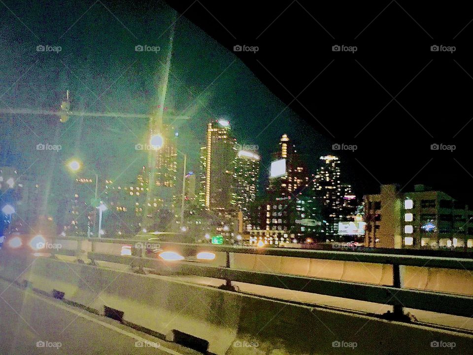 The bright lights of NYC, the “Big Apple” sparkling in all its nocturnal splendor are further enhanced here by street lanterns and the headlights of cars zooming by across the “Pulaski Bridge” in LIC, Queens. 2022. Hypnotic Productions
