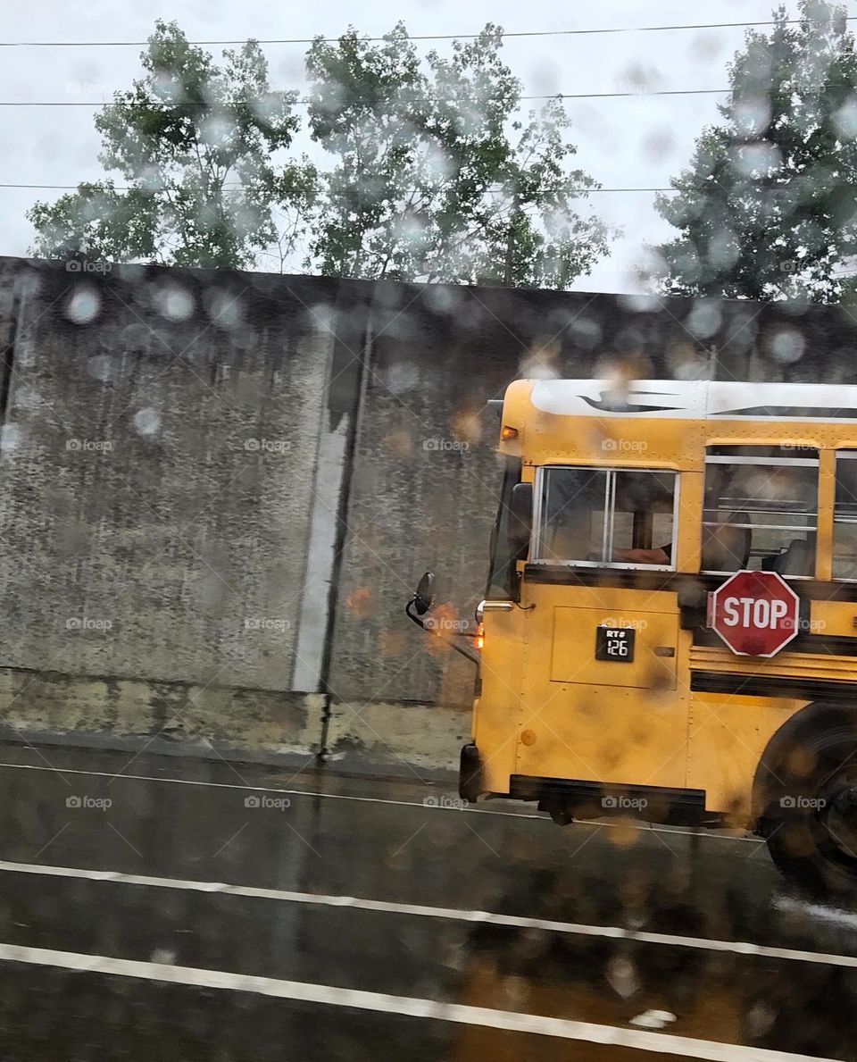 yellow bus driving through the rainy Oregon morning commuter traffic to deliver children to school