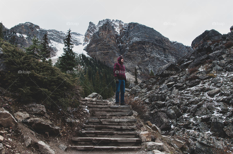 man standing against snowcapped mountains during winter