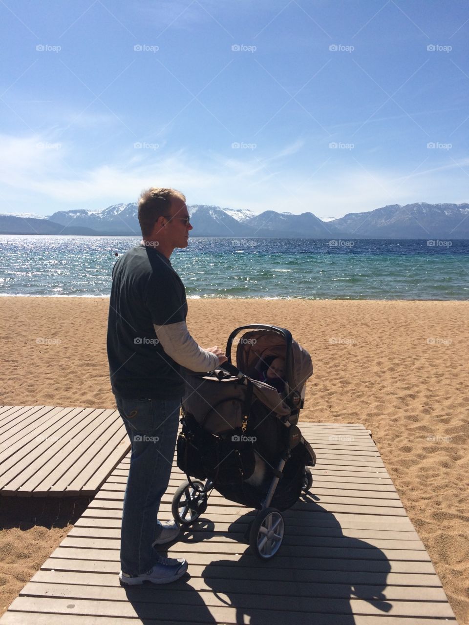 Father with Stroller. At Lake Tahoe a father stands with a baby stroller on the beach