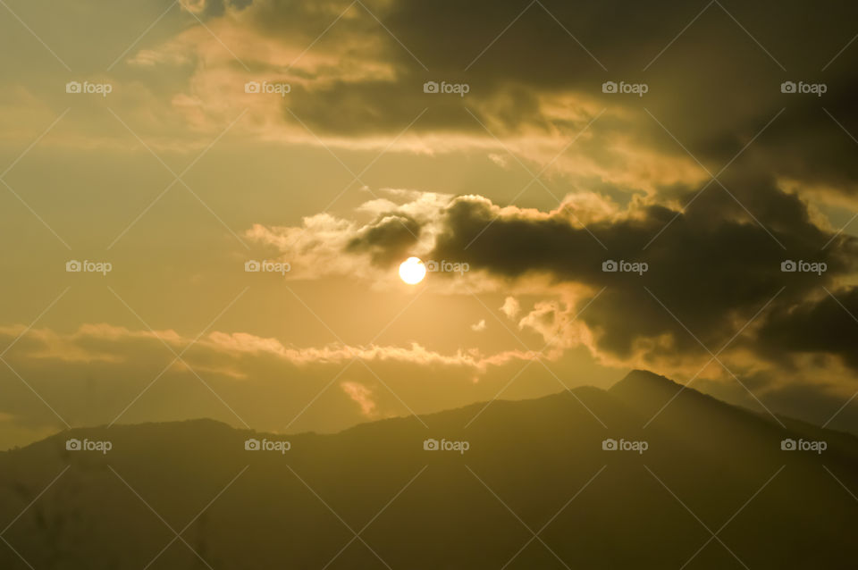 sky with clouds and sun. Storm clouds and orang sky. Sunlight rays in reflects clouds. Beautiful light orange sky and white cloudy with sunshine. Color shade of nature background.