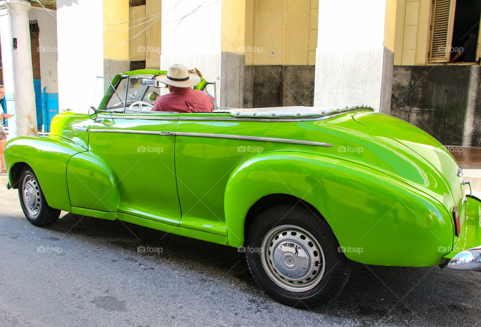 A man driving green classic car in Havana Cuba 