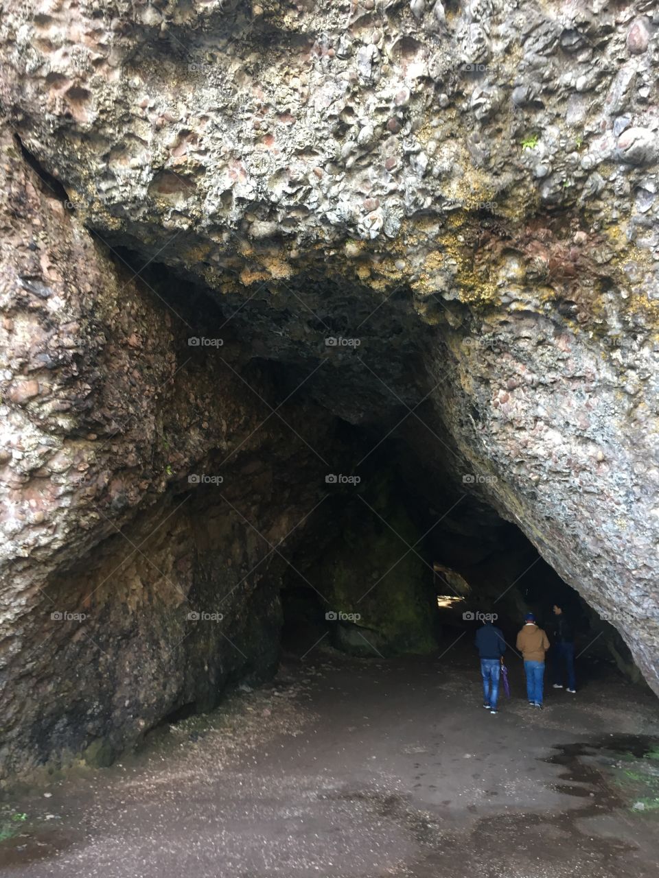 A picture of a cave in Northern Ireland with two people exploring it in the distance 