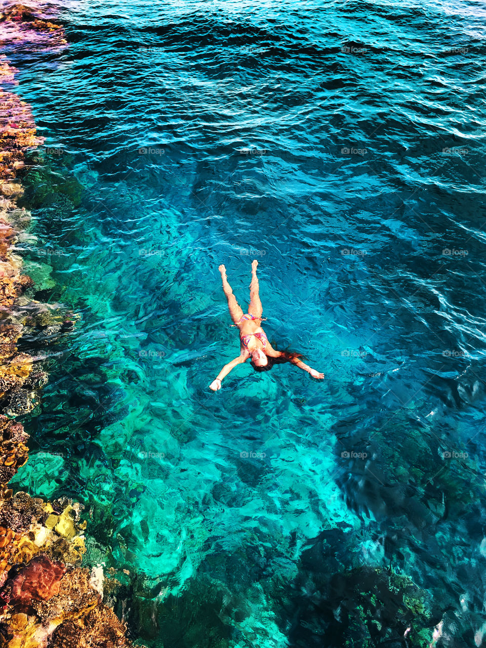 Young woman swimming in the blue sea at the coral reefs 