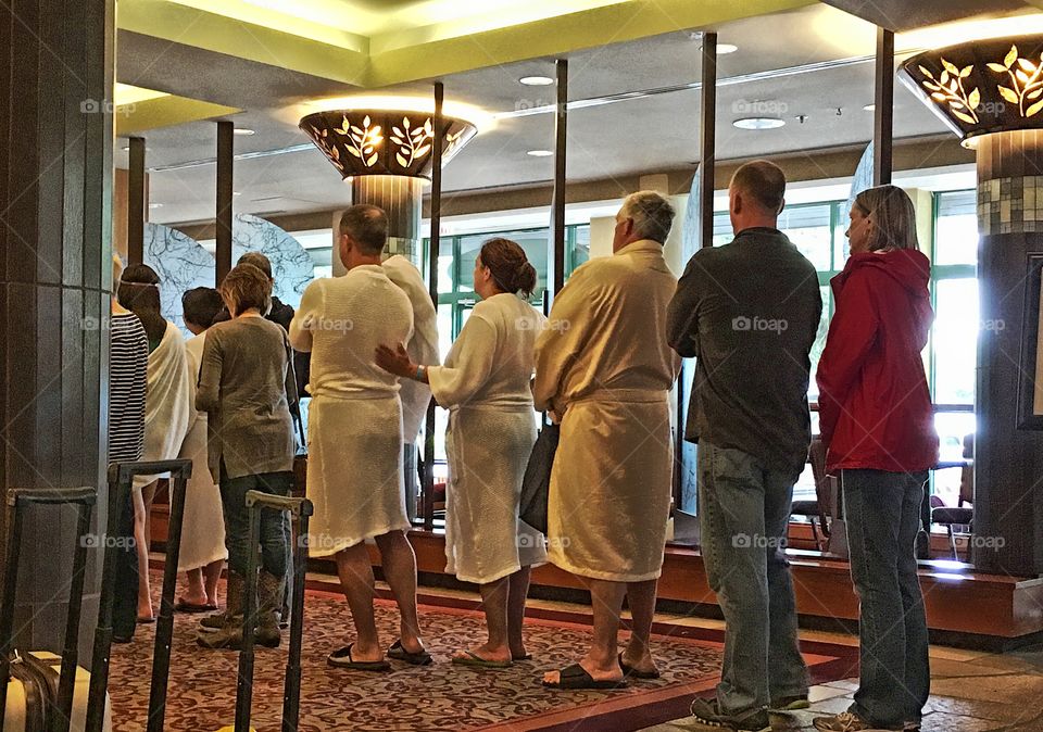 People in white spa bathrobes lined up in hotel lobby, Harrison hot springs resort