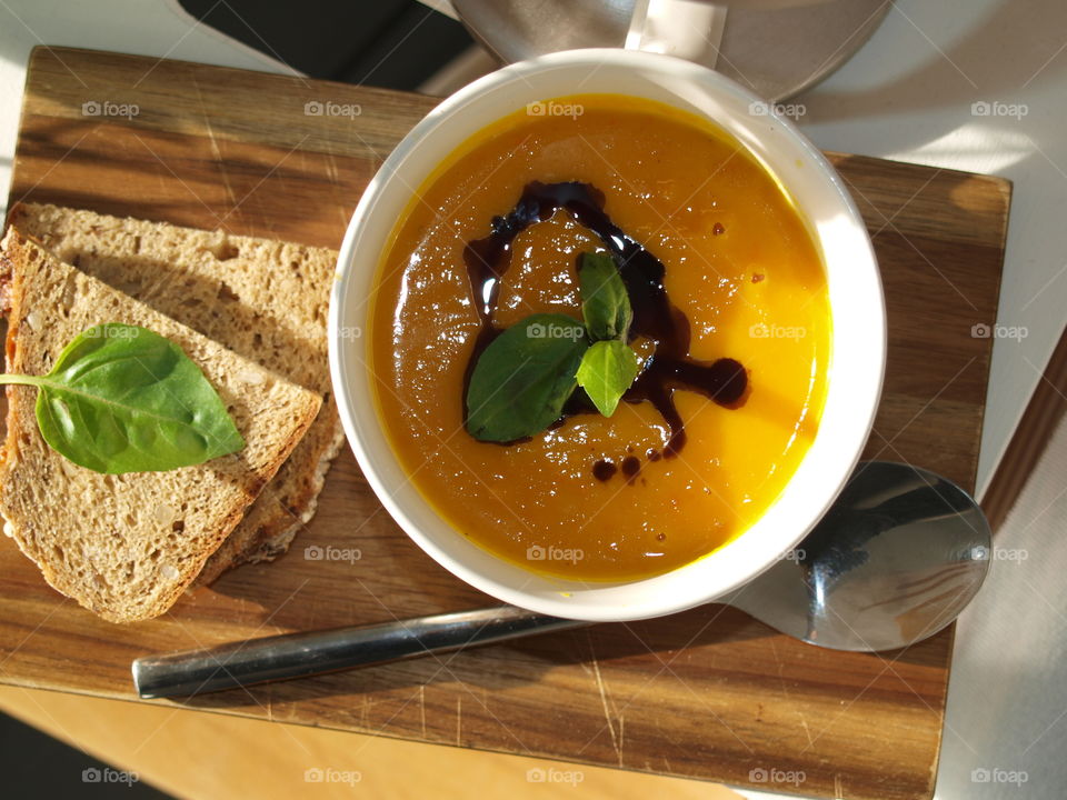 pumpkin soup decorated with basil and fresh bread on the side