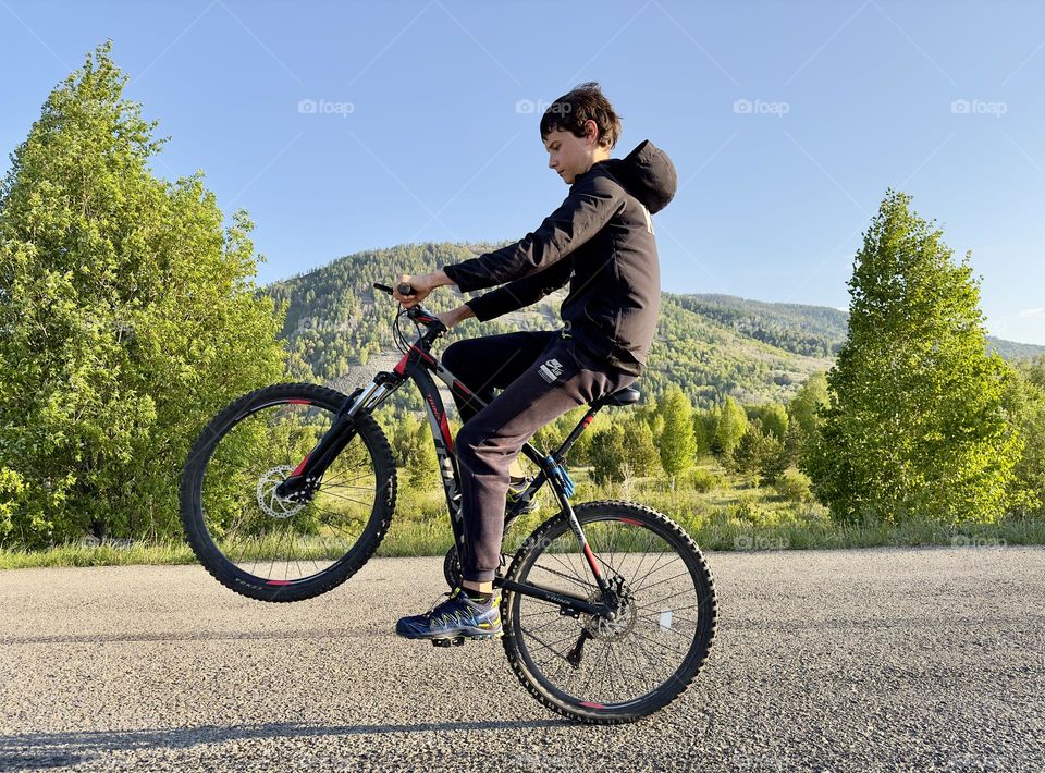 boy riding a bicycle on one wheel