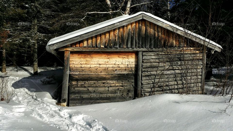 A boat shed near a snowy lake on a sunny winter day