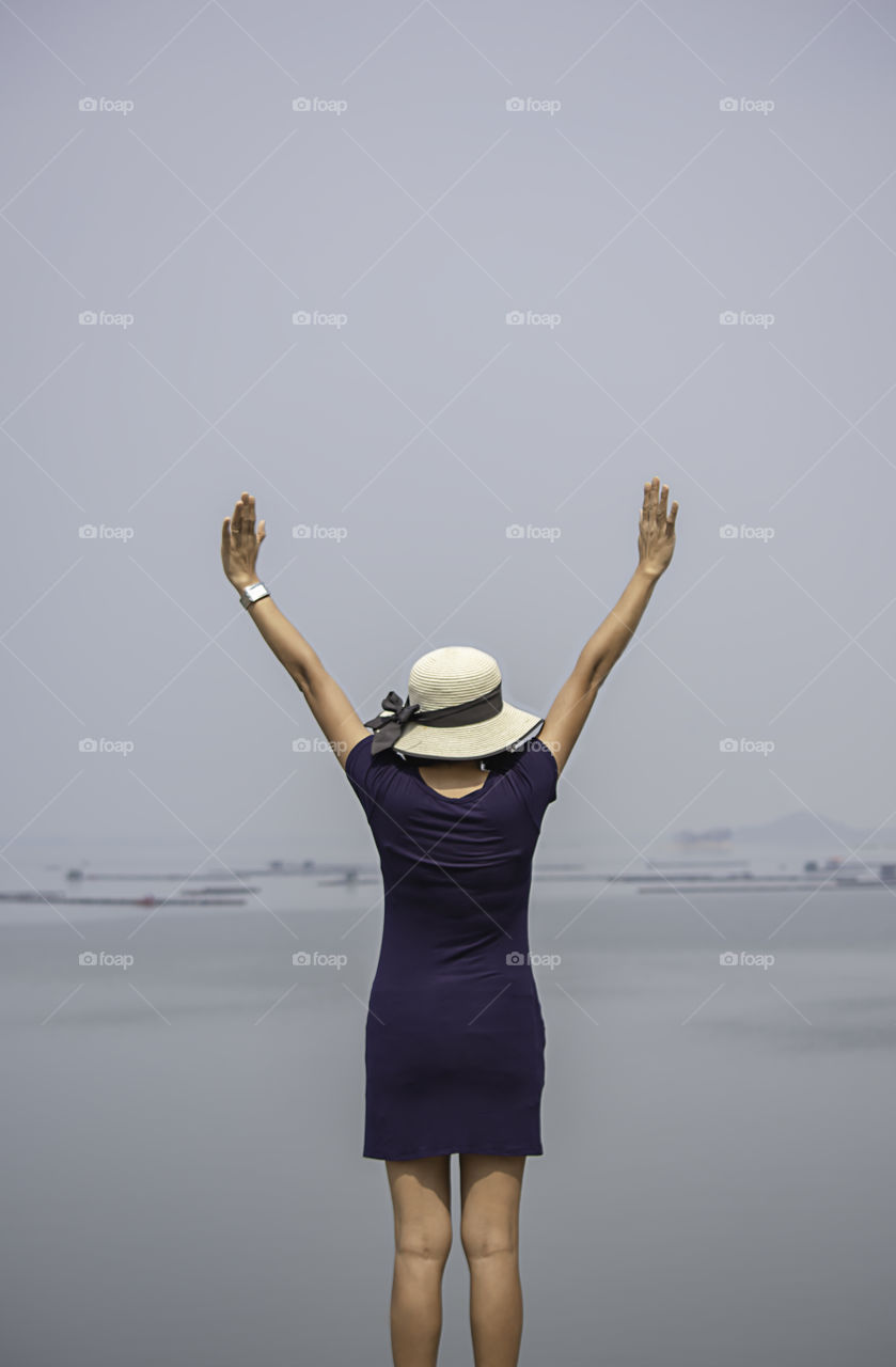 Women raise their arms Background The raft floating fish farming at Krasiew dam ,Supanburi Thailand.