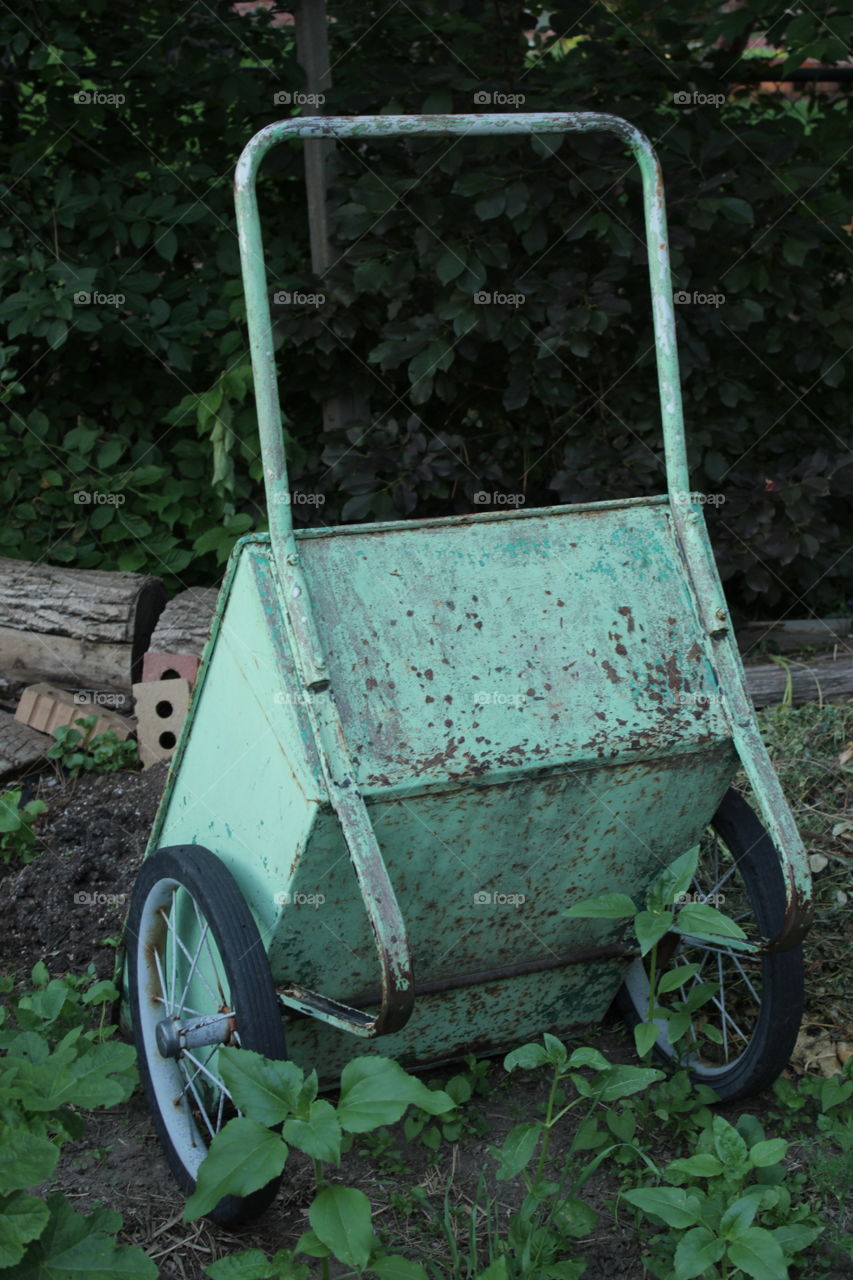 Turned over rusty green wheelbarrow
