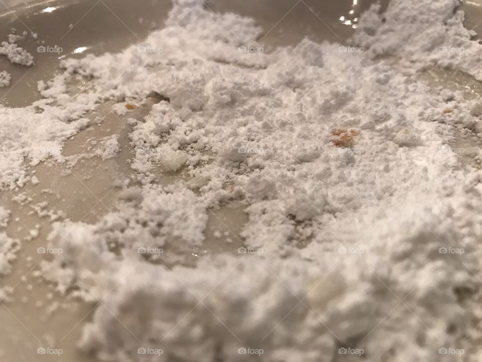 Powdered sugar on a white plate close up.