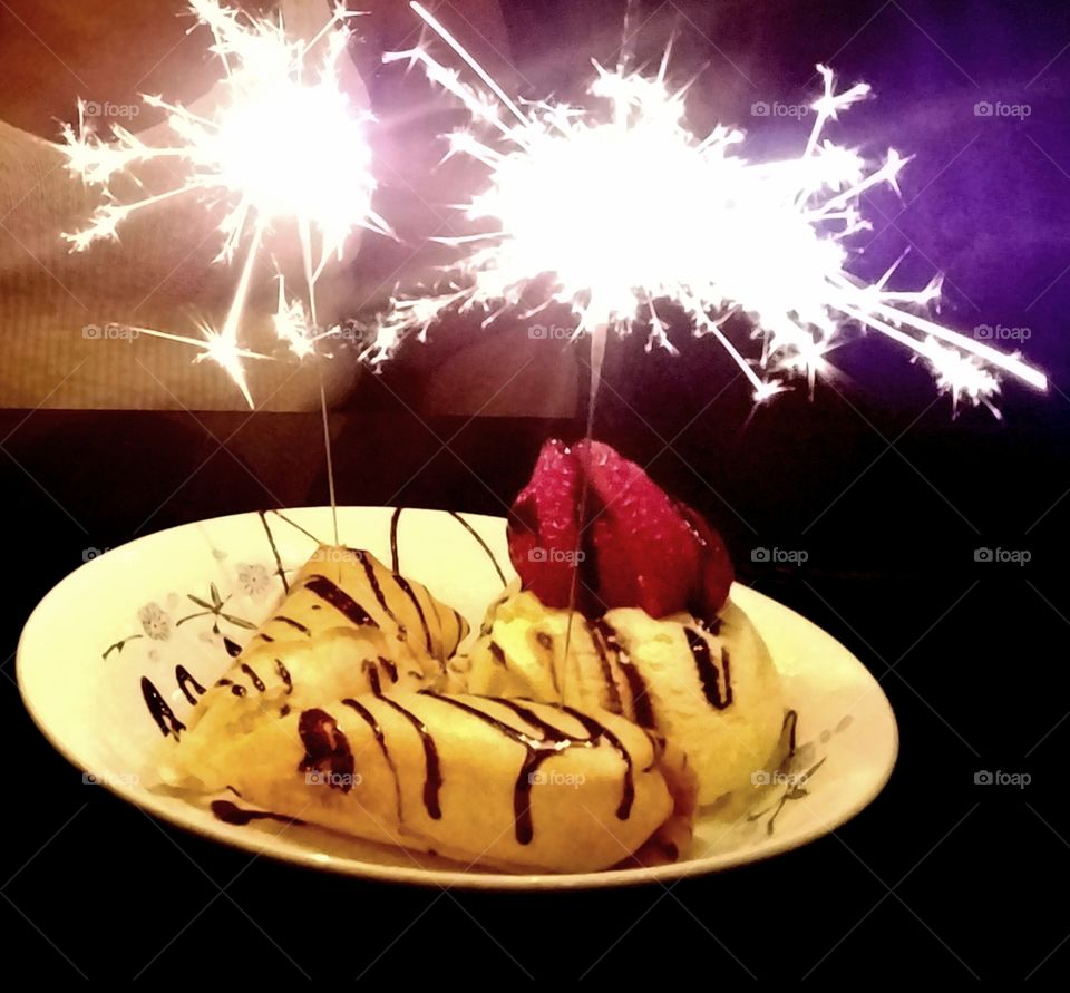 Xango cheesecake with chocolate syrup, a strawberry, and birthday sparklers.