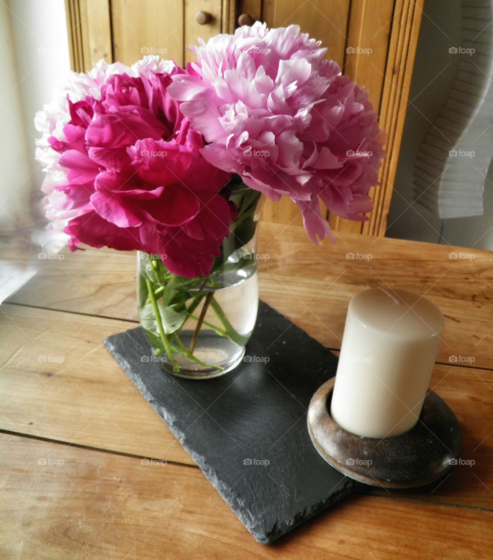 Bouquet de pivoines et bougie avec une décoration intérieure en bois