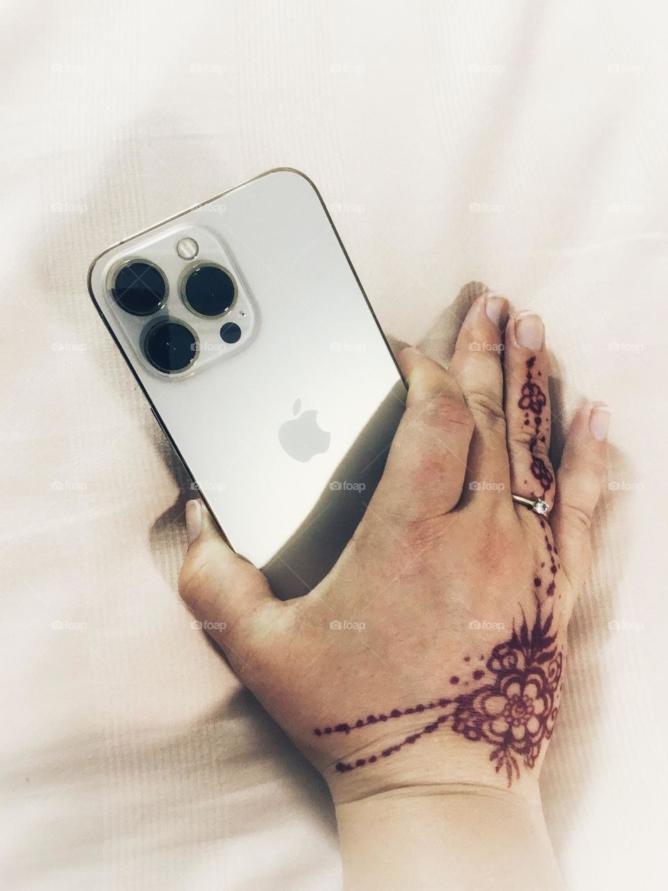 Hand with henna tattoo holding on to iPhone.