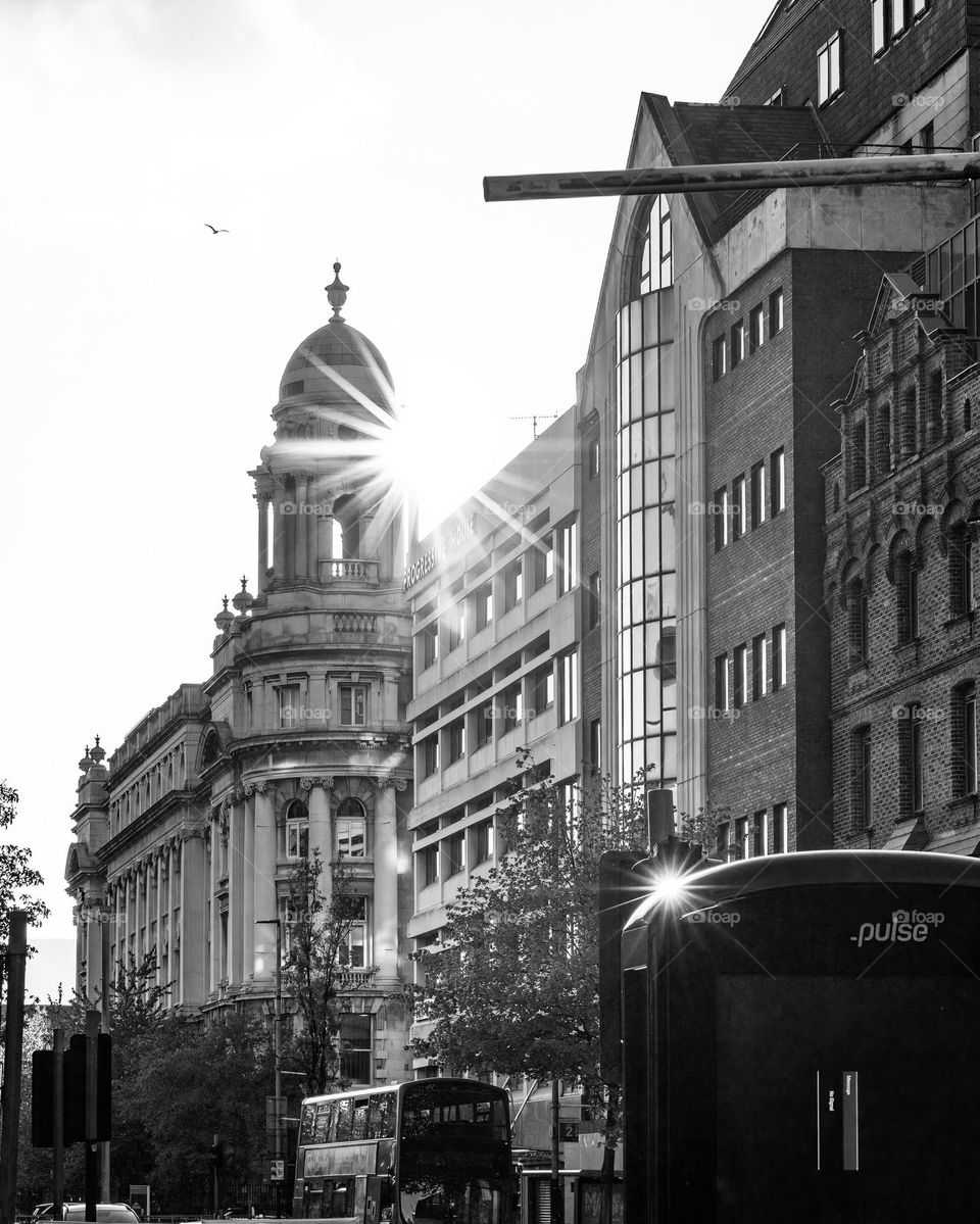 Old stone tower building with the sun creating a star burst in black and white.