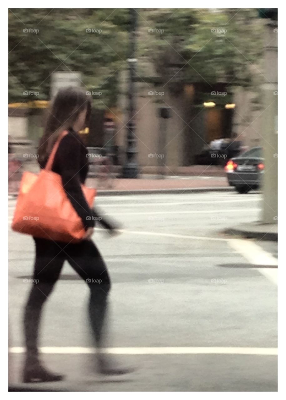 Busy in San Francisco . A girl captured on camera in motion crossing the street on a busy San Francisco morning.