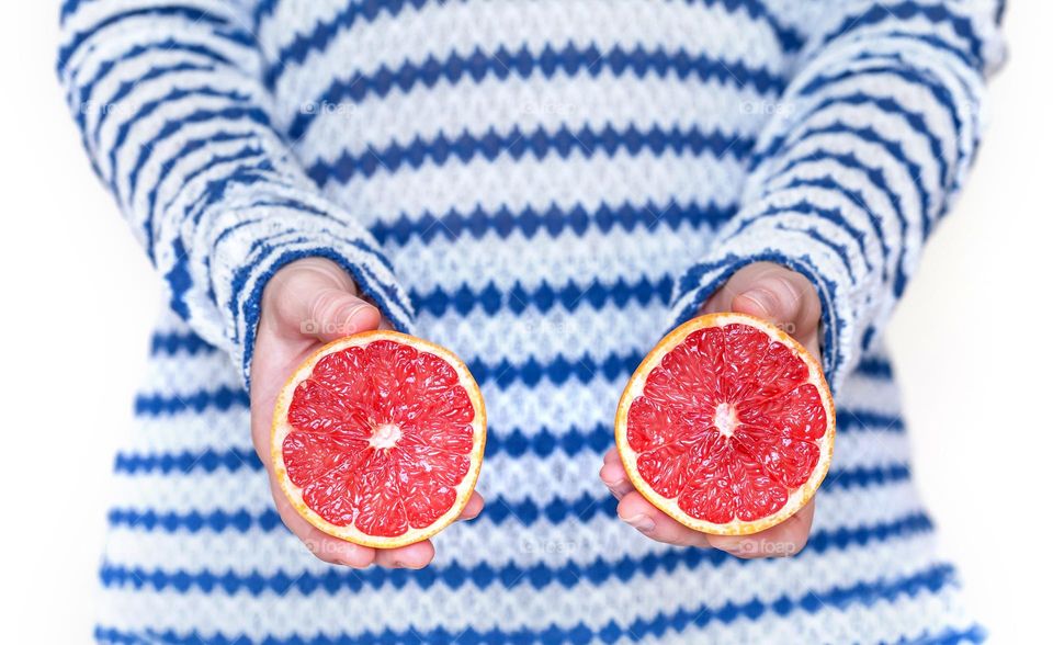 Juicy grapefruit in hands cut in half