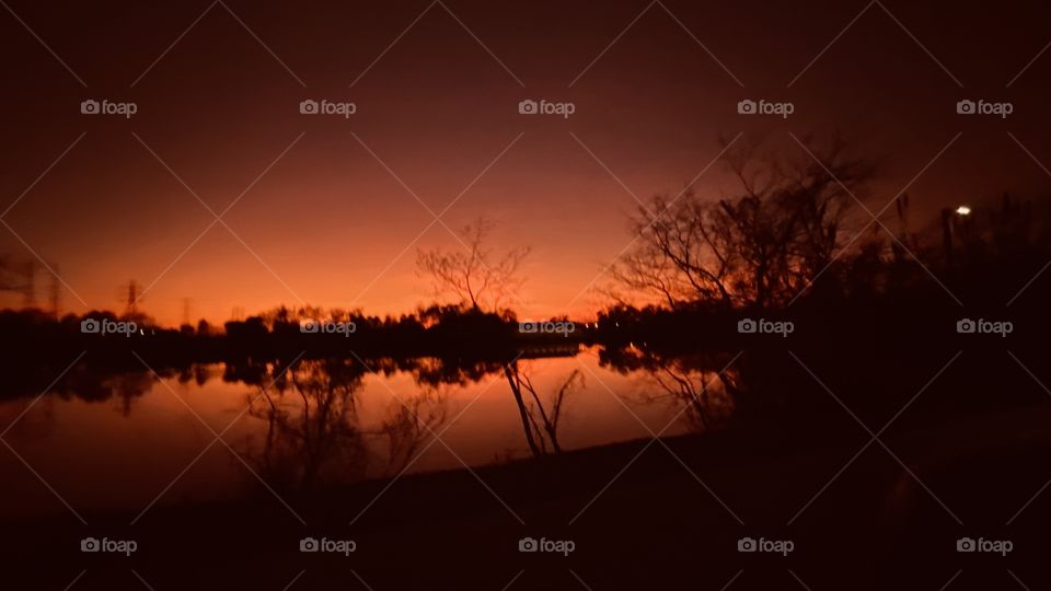 Sunset is over Twilight has arrived and is strong lakebed trees, reflections, calm lake water, deep orange setting make a beautiful picture. 