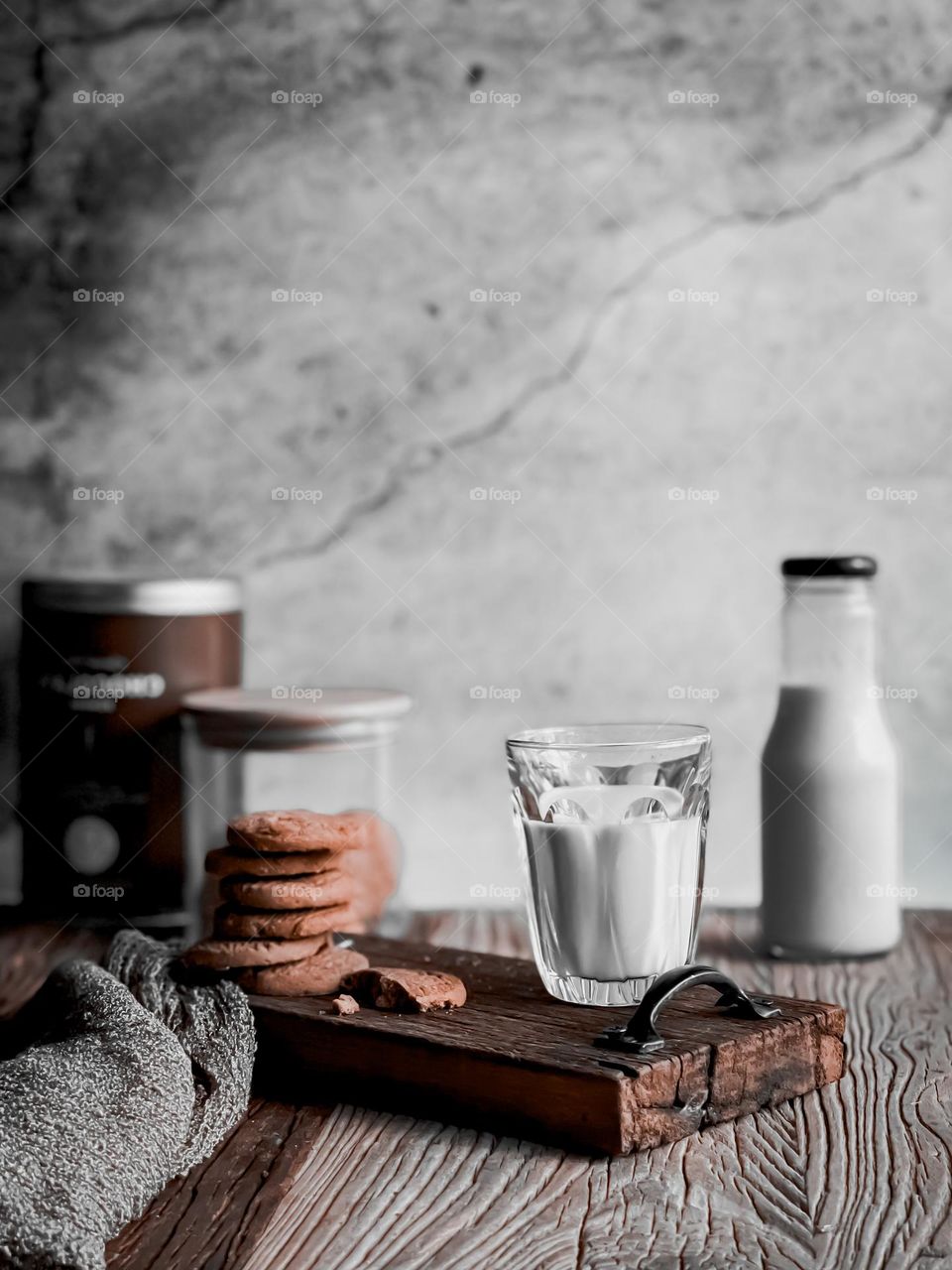 Warm milk and biscuits on a wooden board and a bottle of milk at the back