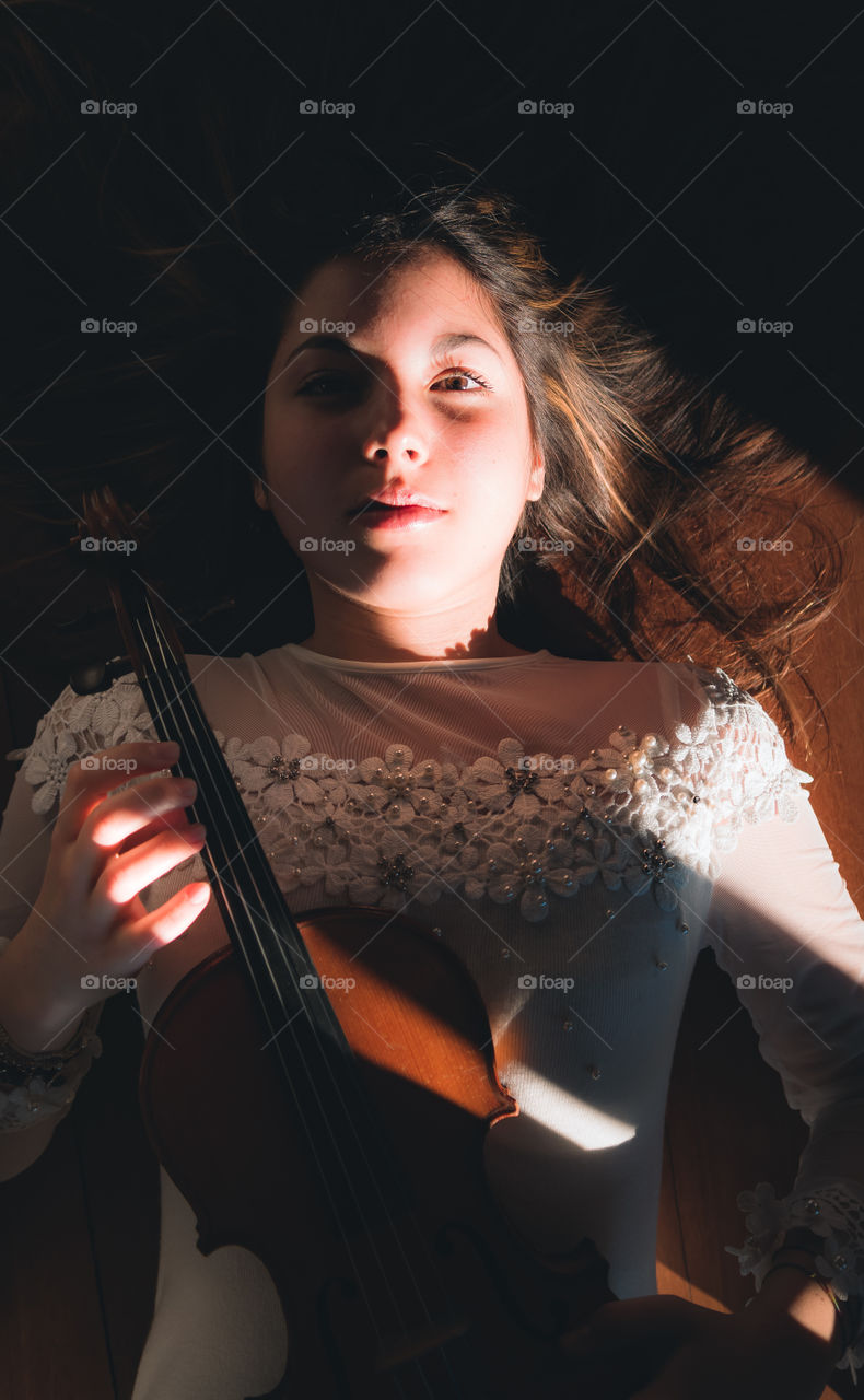 Girl holding a violin in the house